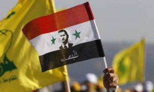 A supporter of Lebanon's Hezbollah waves a Syrian flag depicting Syria's President Bashar al-Assad as other supporters wave Hezbollah flags